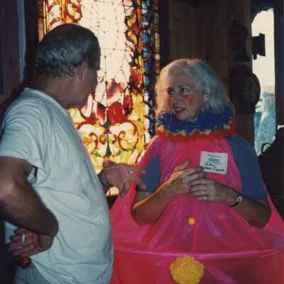 Two unknown people talking, one is dressed up.