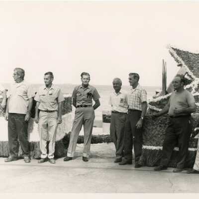 A group of unknown men standing around a float