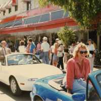 2 unknown people sitting on the top of a convertible going down Duval Street.