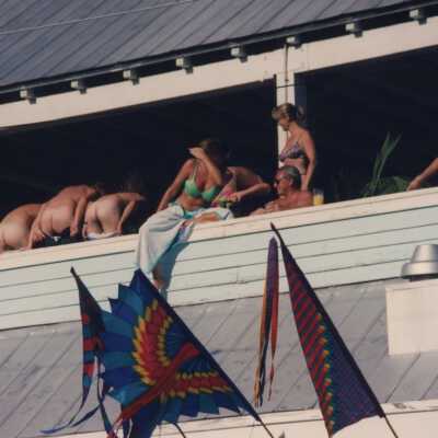 Unknown people on a balcony, men are mooning the crowd below.