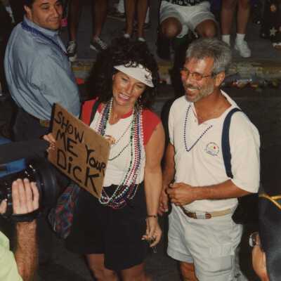 Unknown people walking in the street holding a sign.