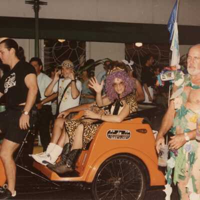 Unknown people on a pedicab dressed up, and many walking around.