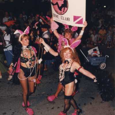 Unknown woman dressed up and holding a sign that says All Woman's dive club.