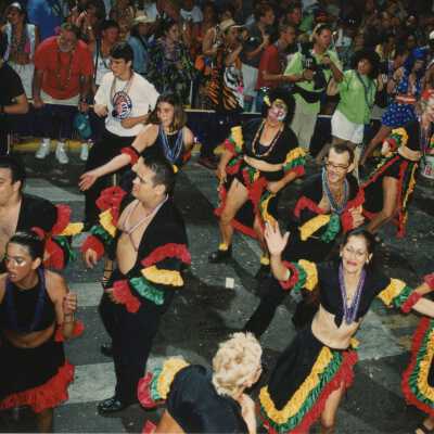 A group of unknown people dressed up dancing in the street for the parade.