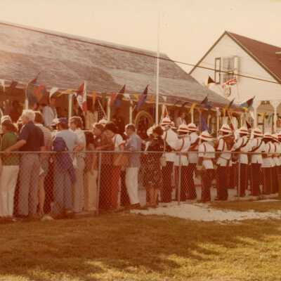 An unknown group of people standing against a fence