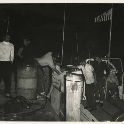 A group of unknown men on a boat jumping on to another boat