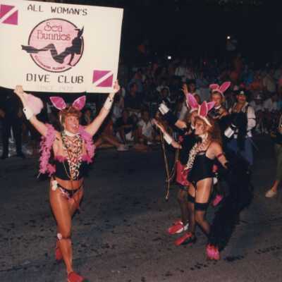 Unknown woman dressed up and holding a sign that says All Woman's dive club.