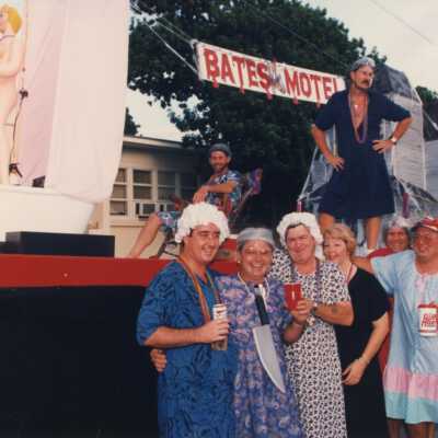 Unknown people dressed up standing in front of a float that reads Bates Motel.