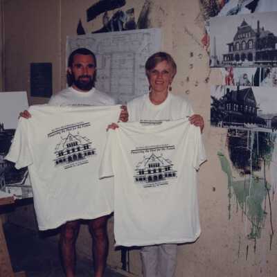 An unknown man and woman holding up t-shirts that have the Custom House on it.