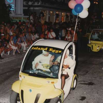 Unknown people driving electric cars in the parade that read Island Eggs.