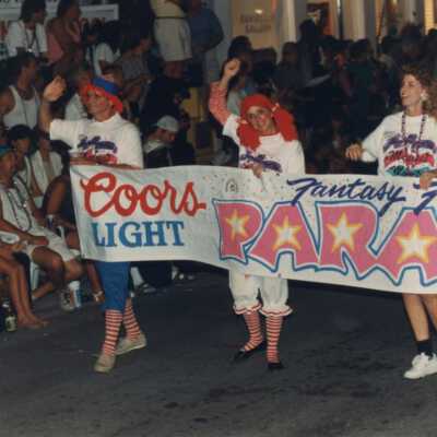 Unknown woman in the parade holding a Coors Light Fantasy Fest parade sign.