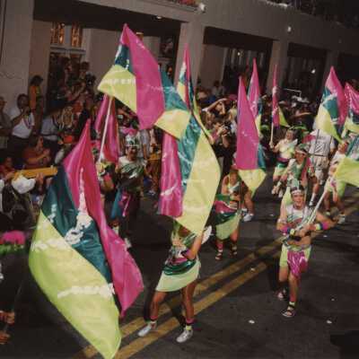 An unknown group of people dressed up walking in the street for the parade.