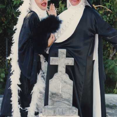 Two unknown people dressed up and standing a the cemetery.