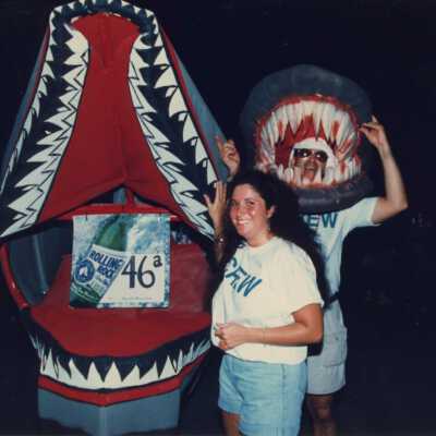Unknown people standing next to a rolling rock sign in a huge mouth.