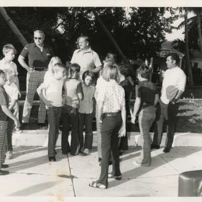 A group of unknown adults and children standing outside