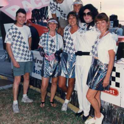 Unknown people dressed up standing in front of a float.