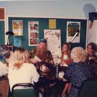 A group of unknown people sitting at a table making face mask.