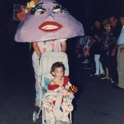 Unknown woman dressed up pushing a child dressed up in a stroller.