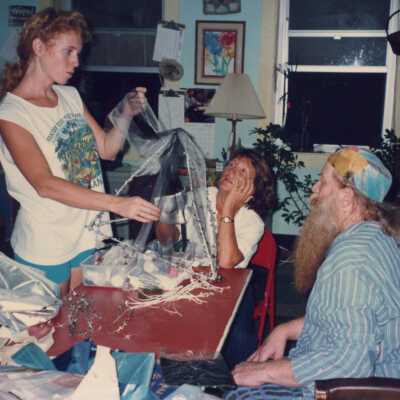 Three unknown people in a house making costumes.