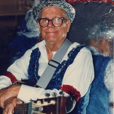 Unknown man dressed up holding some sort of instrument.