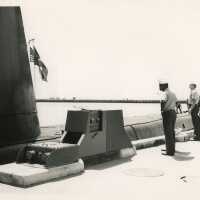 A submarine with men in uniform standing near by