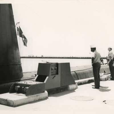 A submarine with men in uniform standing near by