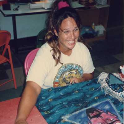 Unknown lady sitting at a table with a painting in front of her.