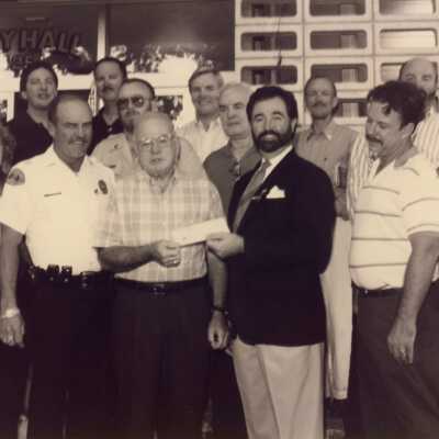 Unknown group of people standing in front of the City Hall. One is accepting a check.