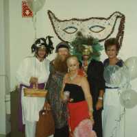 A group of unknown people dressed up and an pink poodle.