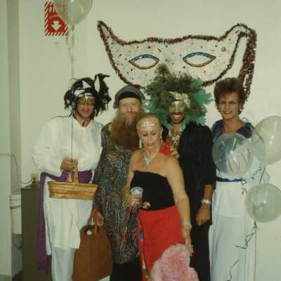 A group of unknown people dressed up and an pink poodle.