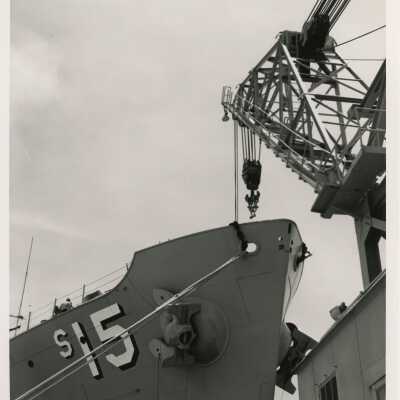 Navy Ship with a crane next to it