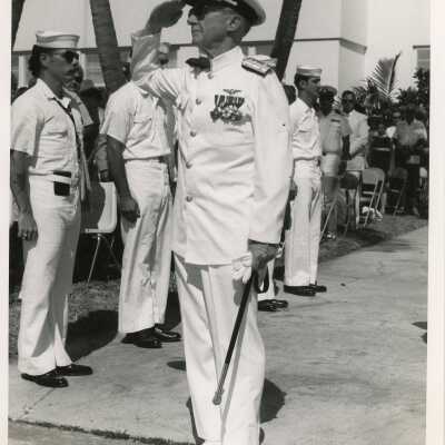 An unknown man in uniform standing at attention with others standing around