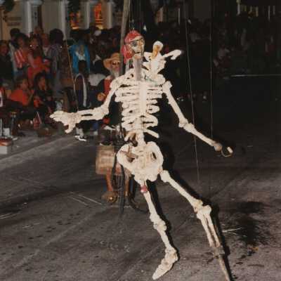An unknown man on a bike holding a skeleton.