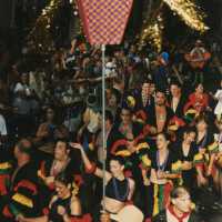 A group of unknown people dressed up dancing in the street for the parade.
