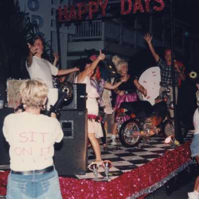 Unknown people dressed up on a float that reads Happy Days.