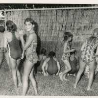 A group of unknown kids in a yard with swim suits on
