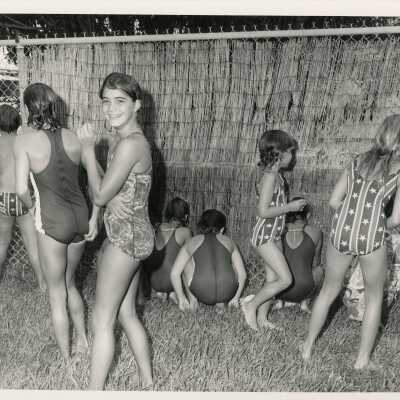 A group of unknown kids in a yard with swim suits on