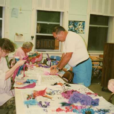 Unknown people working on crafts at a table.