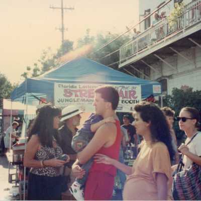 Unknown people standing around the Florida lottery booth at the street fair.