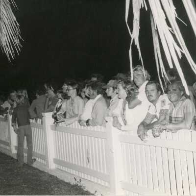 A group of people standing against a fence