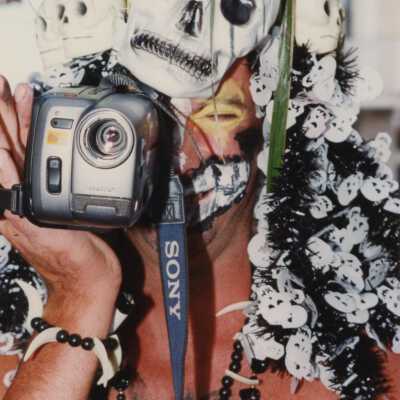 Unknown man dressed up holding a video camera.