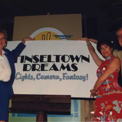Rita Troxel and an unknown man and woman holding a sign that reads Tinseltown Dream.