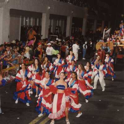 Unknown people dressed up dancing in the street in the parade.