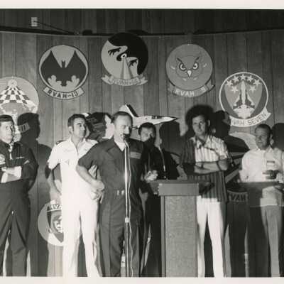A group of men at a ceremony talking at the microphone