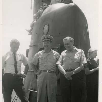 U.S. Navy men and unknown people standing next to a submarine