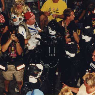 A group of unknown people dressed up walking in the street.