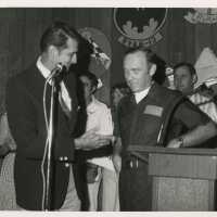 2 Unknown men talking into microphones at a ceremony