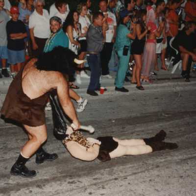 Unknown man dressed up dragging a doll down the street during the parade.