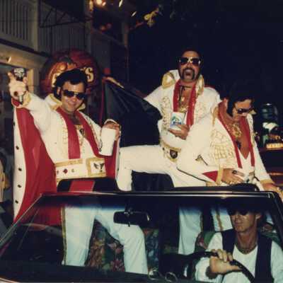 Unknown men dressed up in a convertible in the parade.