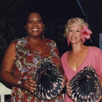 Two unknown woman each holding an award at the awards ceremony.
